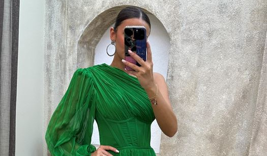 Une femme dans une longue robe verte se prend en photo devant le miroir